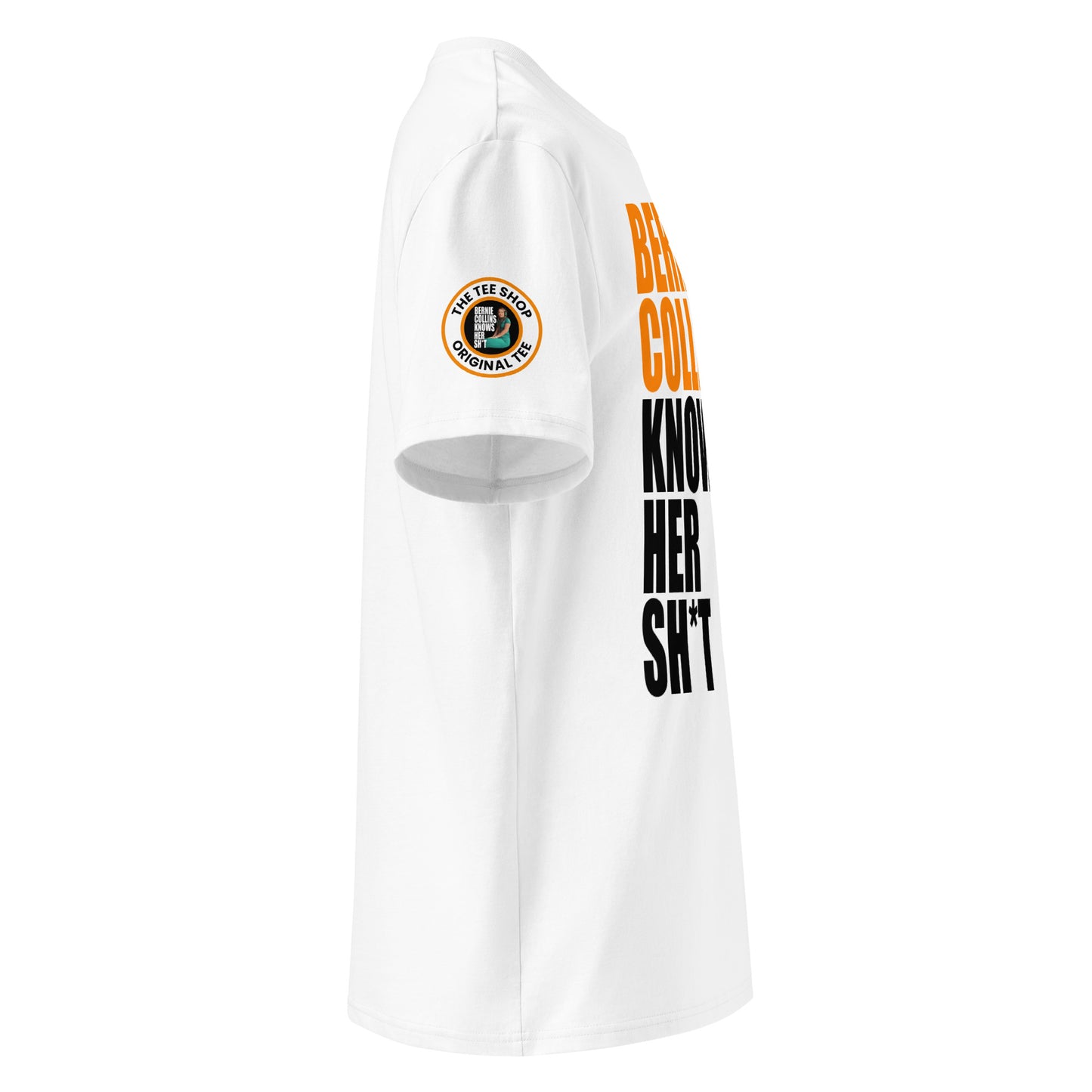 Right side view of white t-shirt showing The Tee Shop donut logo patch on the sleeve and edge of the papaya and black “BERNIE COLLINS KNOWS HER SH*T” slogan. DTF print, McLaren F1 fan style.