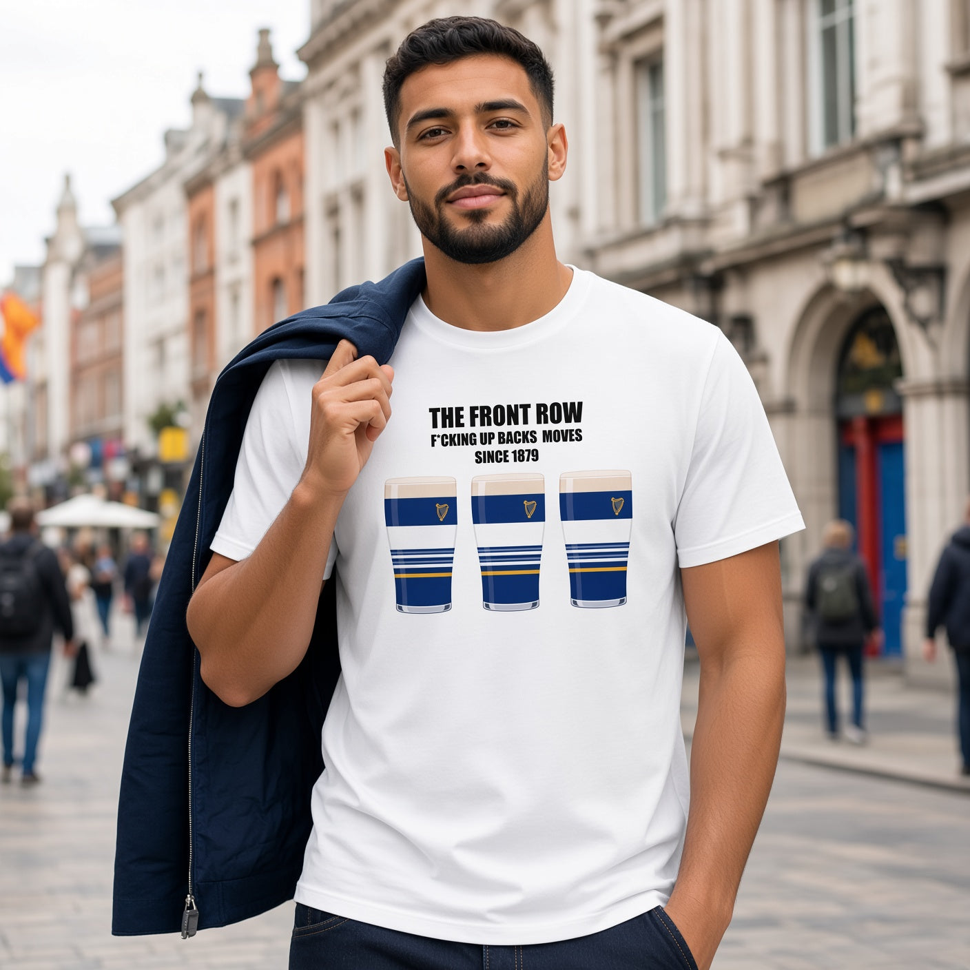 Male model wearing a white Leinster rugby t-shirt reading “The Front Row - F*cking Up Backs Moves Since 1879” with three blue striped pint graphics featuring a harp crest, styled with a jacket for Leinster supporters