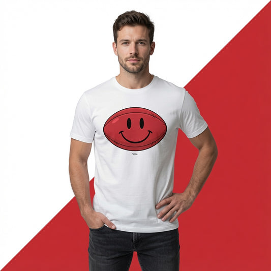A man wearing a white crewneck t-shirt with a red rugby ball smiley face graphic on the chest, posed against a split white and red background.
