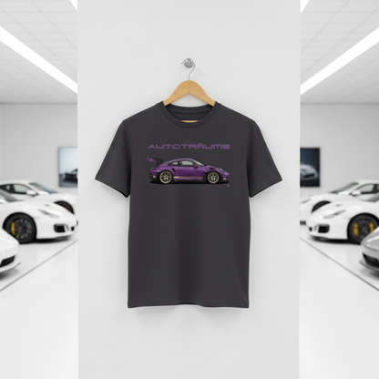 Anthracite AUTOTRÄUME GT3 T‑shirt with a purple Porsche‑style car illustration hanging on a premium wooden hanger and silver wall peg against a central white wall in a bright sports car gallery, with a glossy white floor and blurred white and silver sports cars running down both sides.
