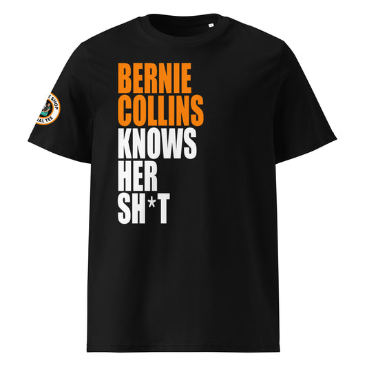 Front view of black unisex t-shirt with bold slogan: “BERNIE COLLINS” in McLaren papaya orange and “KNOWS HER SH*T” in white, stacked vertically. DTF print, perfect for McLaren and F1 fans.