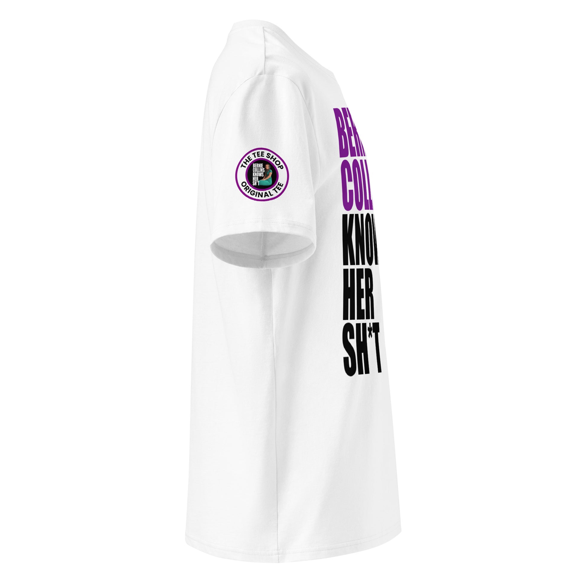 Right side view of white t-shirt showing The Tee Shop donut logo patch on the sleeve and edge of the purple and black “BERNIE COLLINS KNOWS HER SH*T” slogan. DTF print, F1 purple sector fan style.