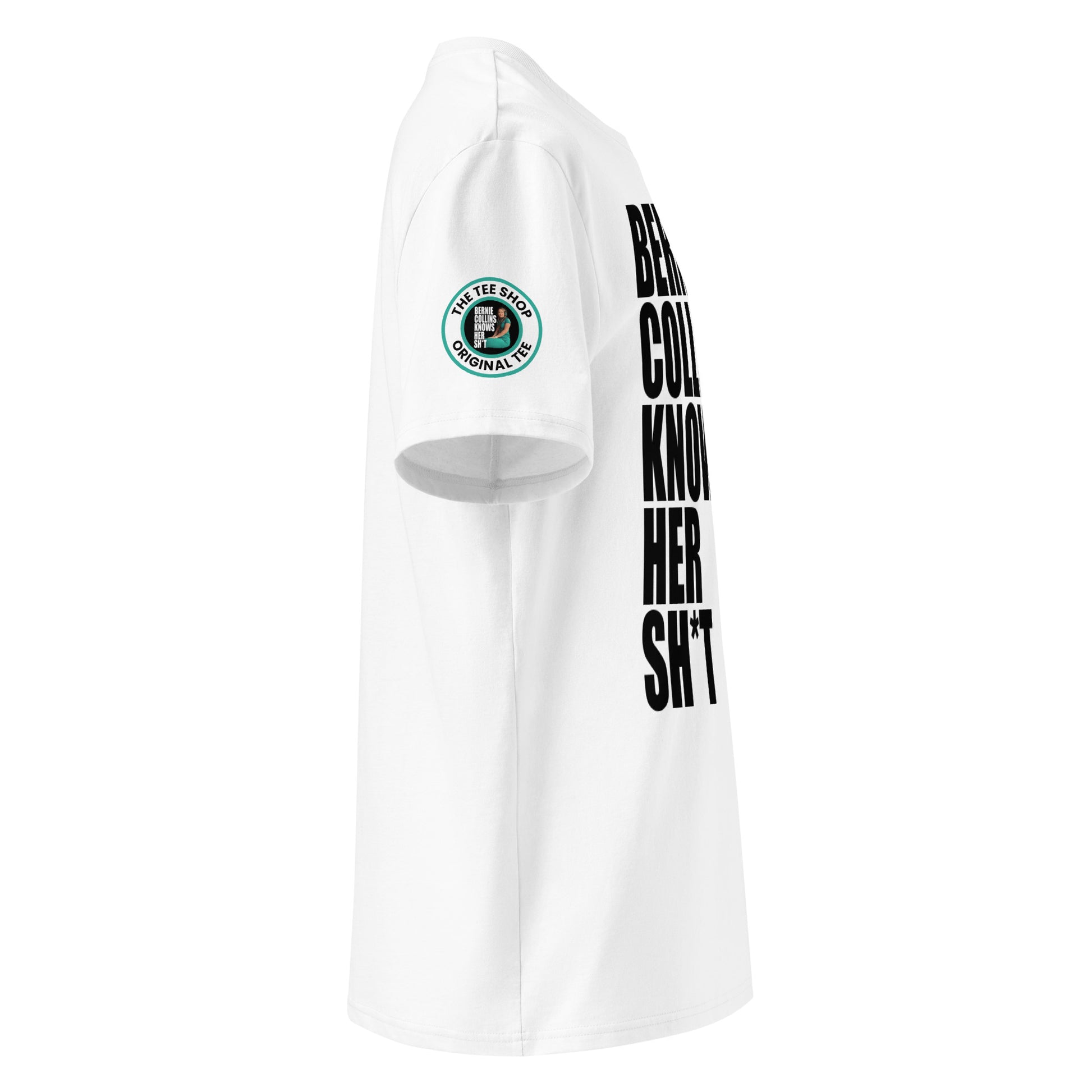 Right side view of white t-shirt showing The Tee Shop donut logo patch on the sleeve and edge of the bold “BERNIE COLLINS KNOWS HER SH*T” slogan. DTF print, F1 pundit tribute.