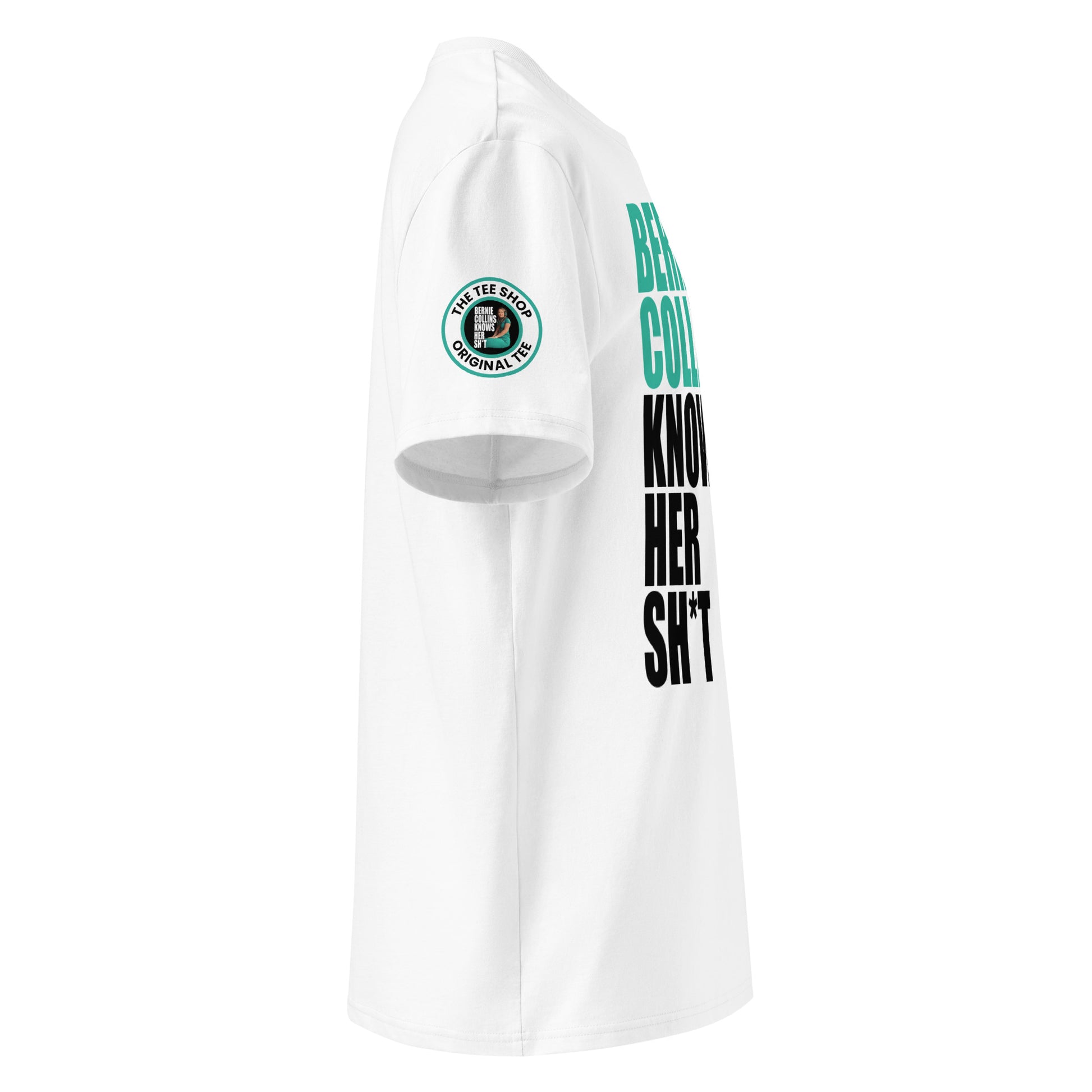 Right side view of white t-shirt showing The Tee Shop donut logo patch on the sleeve and edge of the teal and black “BERNIE COLLINS KNOWS HER SH*T” slogan. DTF print, Mercedes F1 fan style.