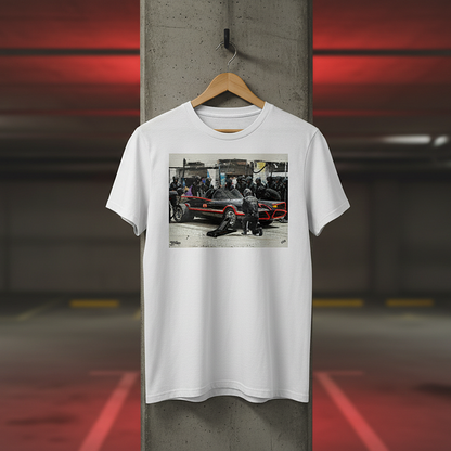 White Bat Stop Graffiti T‑Shirt with a black car and red accents pit stop design hanging on a wooden hanger in an underground car park, with concrete background and red lighting.