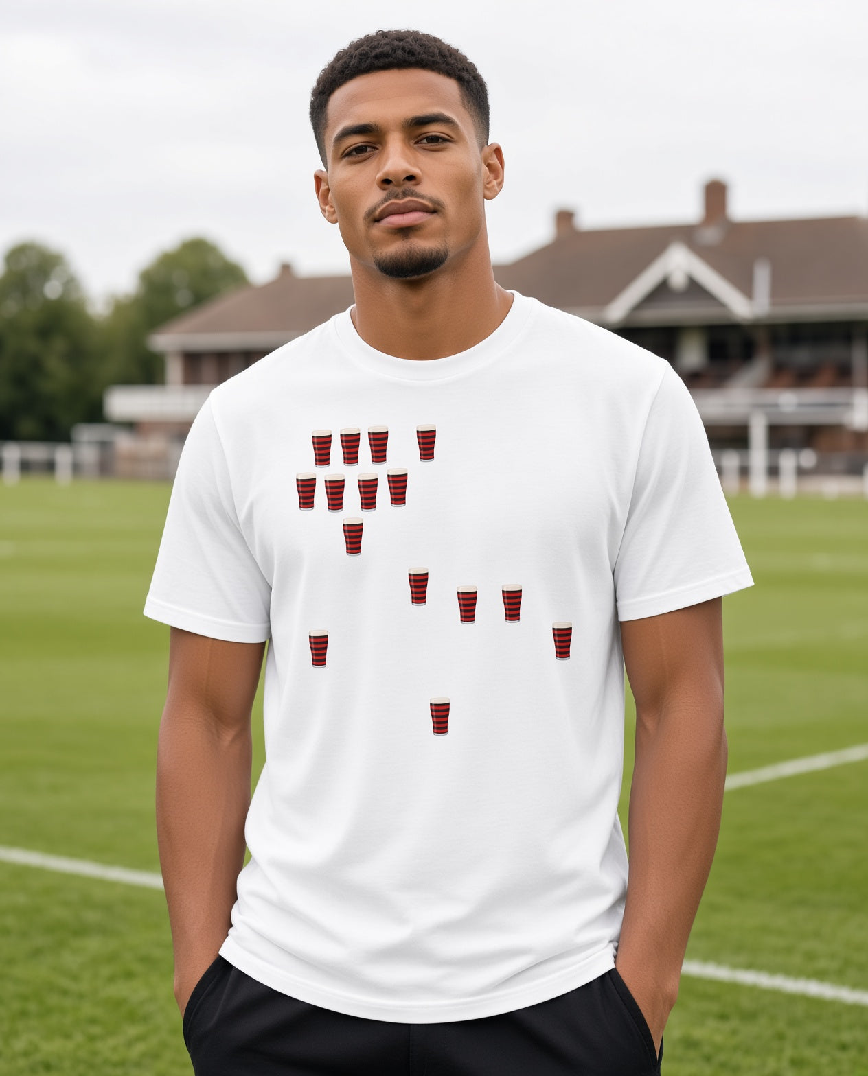 Male model wearing a white Blackheath Team Pints rugby t-shirt with scattered red and black striped pint graphics, photographed at a rugby ground for Blackheath match day supporters in South East London