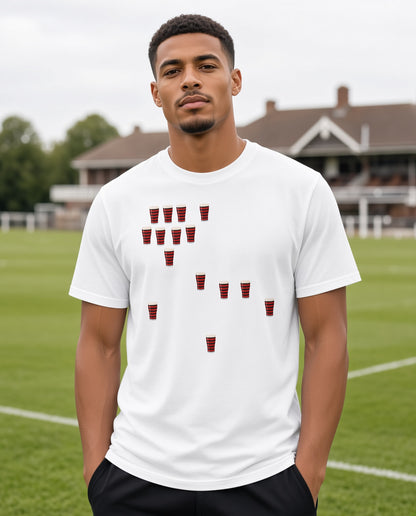 Male model wearing a white Blackheath Team Pints rugby t-shirt with scattered red and black striped pint graphics, photographed at a rugby ground for Blackheath match day supporters in South East London
