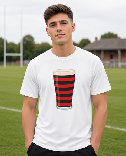 Male model wearing a white Blackheath rugby Mega Pint t-shirt with a red and black striped pint glass graphic, photographed at a rugby ground for Blackheath match days in South East London and England supporters