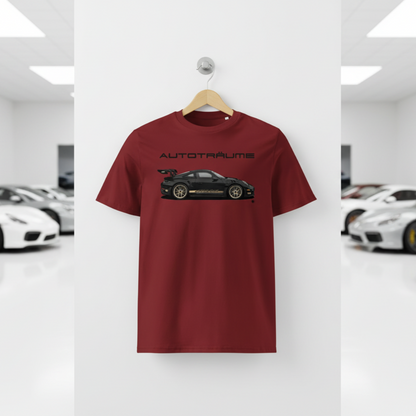 Burgundy AUTOTRÄUME GT3 T‑shirt with a black Porsche‑style car and gold highlights illustration hanging on a premium wooden hanger and silver wall peg against a central white wall in a bright sports car gallery, with a glossy white floor and blurred white and silver sports cars running down both sides.