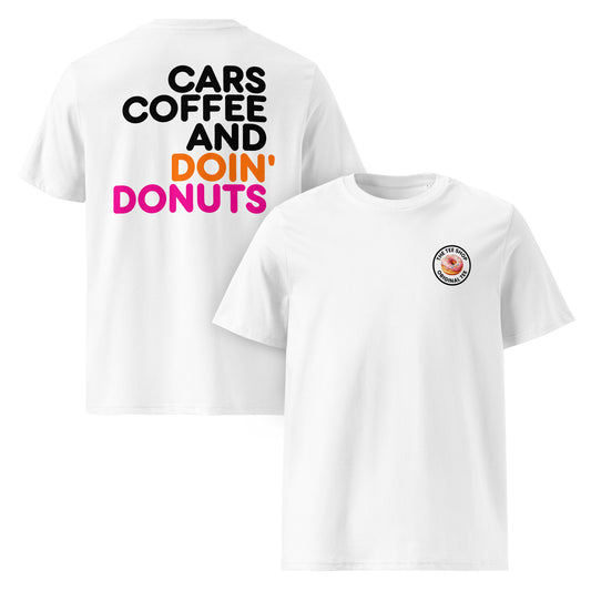 White unisex t-shirt showing large “Cars Coffee and Doin’ Donuts” slogan in black, orange, and pink Impact font printed on the back, with The Tee Shop circular donut logo on the left chest. Plain sleeves, DTF printed, perfect for car meet fans who want a statement back print.