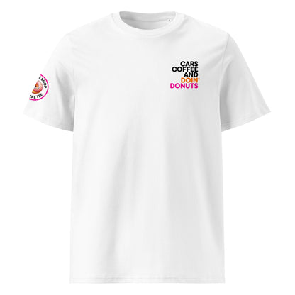White unisex t-shirt with small “Cars Coffee and Doin’ Donuts” slogan printed on the right chest in black, orange, and pink. Features The Tee Shop donut logo patch on the right sleeve. Minimalist car meet tee, DTF printed.