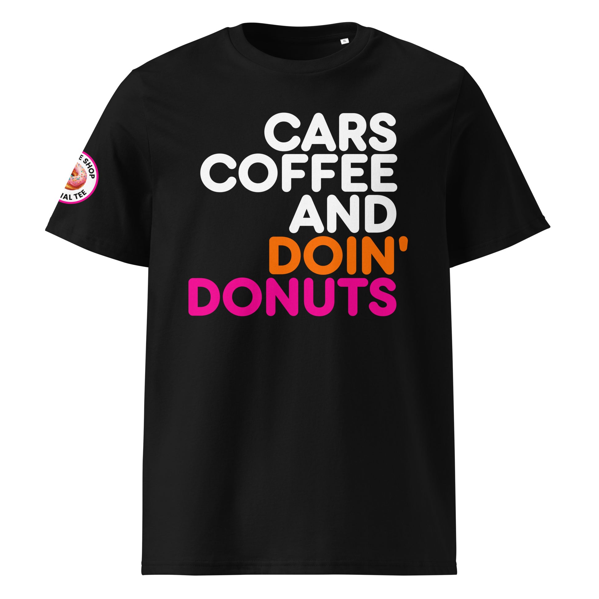 Black unisex t-shirt with bold white, orange, and pink “Cars Coffee and Doin’ Donuts” slogan in Impact font. Features The Tee Shop donut logo patch on right sleeve. DTF printed for vibrant colour. Perfect for car meets and coffee runs.