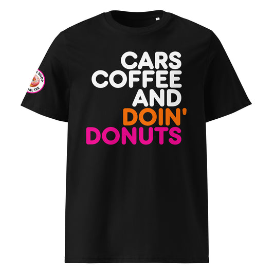Black unisex t-shirt with bold white, orange, and pink “Cars Coffee and Doin’ Donuts” slogan in Impact font. Features The Tee Shop donut logo patch on right sleeve. DTF printed for vibrant colour. Perfect for car meets and coffee runs.