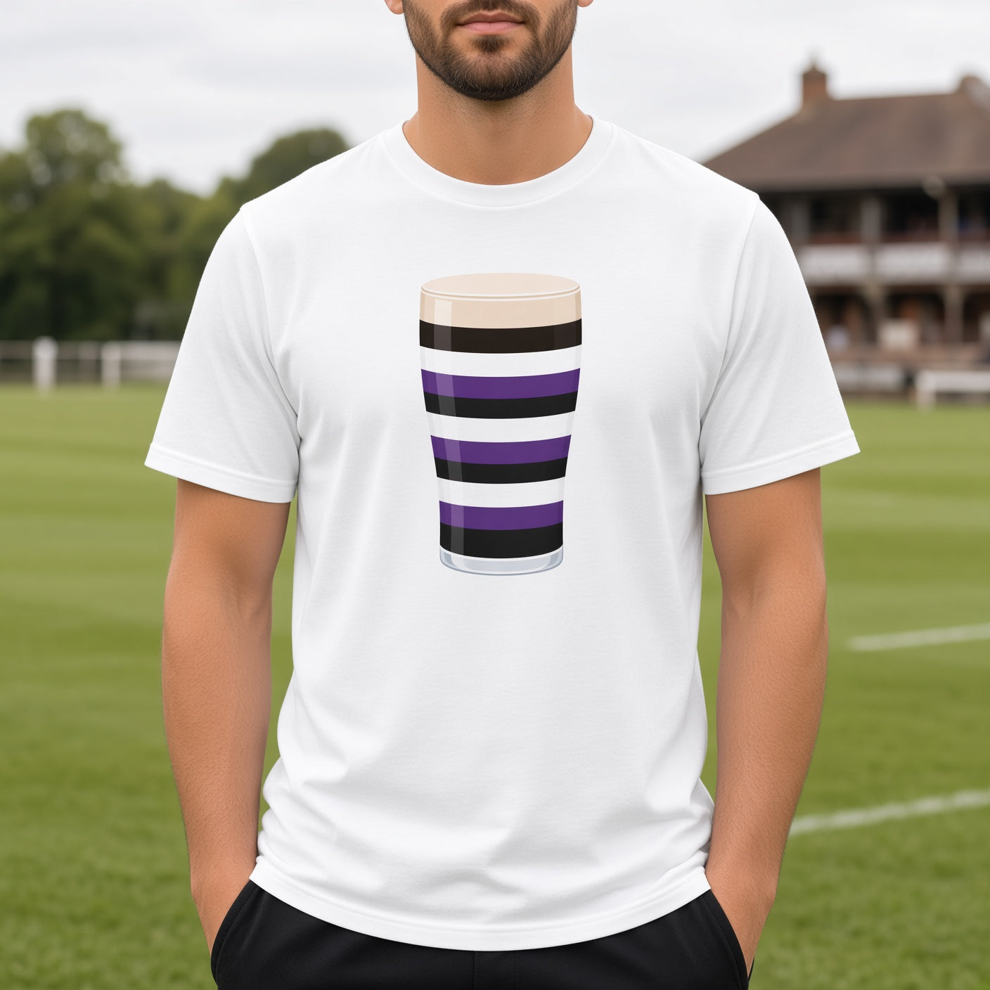 Close-up of the Terenure Mega Pint rugby t-shirt design on a white tee, showing the purple, black and white striped pint glass graphic for Terenure College supporters. Background shows a  rugby club pavilion