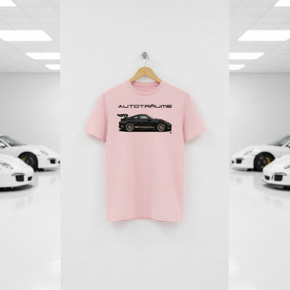 Soft cotton pink AUTOTRÄUME GT3 T‑shirt with a black Porsche‑style car and gold highlights illustration hanging on a premium wooden hanger and silver wall peg against a central white wall in a bright sports car gallery, with a glossy white floor and blurred white and silver sports cars running down both sides.