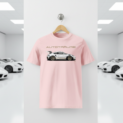 Cotton pink unisex organic cotton AUTOTRÄUME GT3 RS T-shirt featuring a large, centred white Porsche-style GT3 RS car graphic with gold details hanging on a premium wooden hanger with a silver wall peg against a clean white wall panel in a bright modern sports car gallery with glossy floors and blurred white and silver sports cars on both sides.