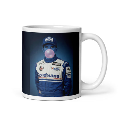 White ceramic 11oz mug featuring a pop-art style portrait of Damon Hill in a blue racing suit and cap, blue-tinted face, and blowing a bubblegum bubble, set against a blue background.