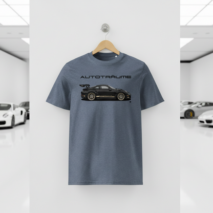 Dark heather blue AUTOTRÄUME GT3 T‑shirt with a black Porsche‑style car and gold highlights illustration hanging on a premium wooden hanger and silver wall peg against a central white wall in a bright sports car gallery, with a glossy white floor and blurred white and silver sports cars running down both sides.
