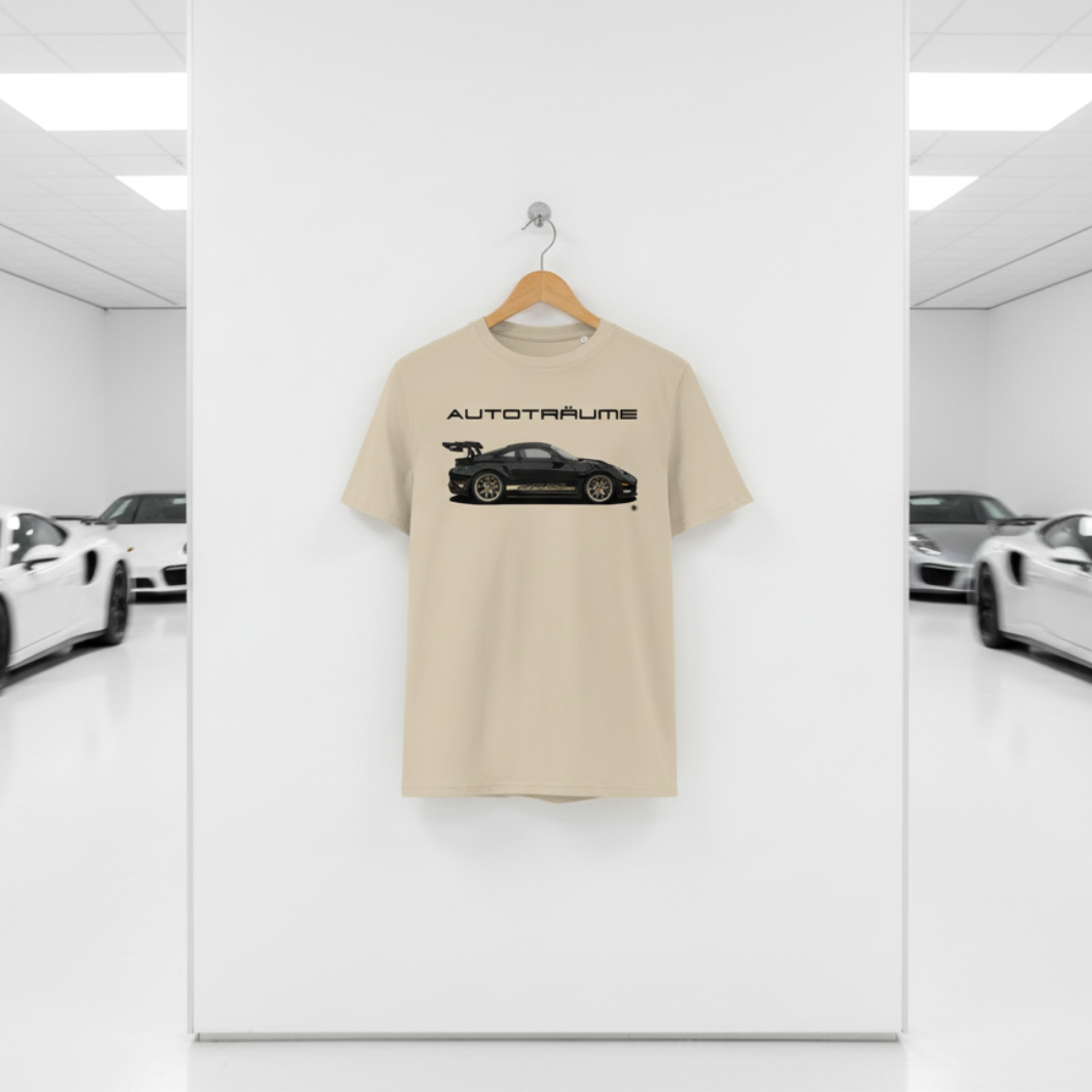 Desert dust AUTOTRÄUME GT3 T‑shirt with a black Porsche‑style car and gold highlights illustration hanging on a premium wooden hanger and silver wall peg against a central white wall in a bright sports car gallery, with a glossy white floor and blurred white and silver sports cars running down both sides.