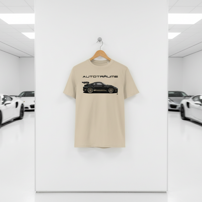 Desert dust AUTOTRÄUME GT3 T‑shirt with a black Porsche‑style car and gold highlights illustration hanging on a premium wooden hanger and silver wall peg against a central white wall in a bright sports car gallery, with a glossy white floor and blurred white and silver sports cars running down both sides.