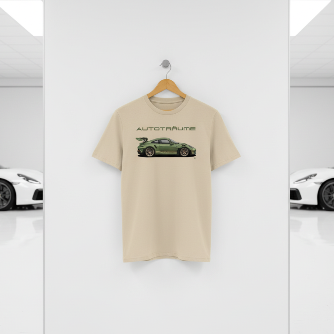 Desert dust AUTOTRÄUME GT3 T‑shirt with an olive green Porsche‑style car illustration hanging on a premium wooden hanger and silver peg against a central white wall in a bright sports car gallery, with a glossy white floor and blurred white and silver sports cars running down both sides.