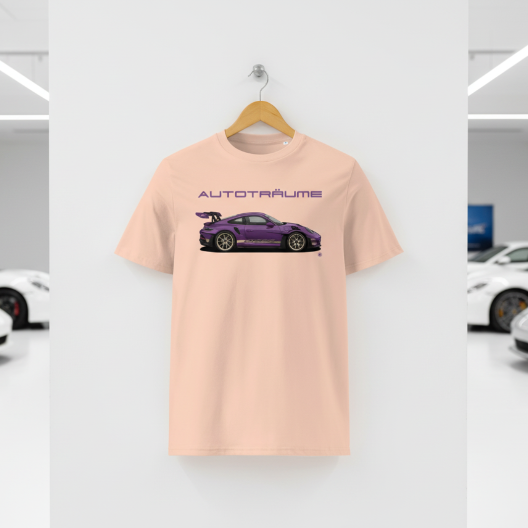 Light peach Fraîche Pêche AUTOTRÄUME GT3 T‑shirt with a purple Porsche‑style car illustration hanging on a premium wooden hanger and silver wall peg against a central white wall in a bright sports car gallery, with a glossy white floor and blurred white and silver sports cars running down both sides.
