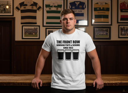 Young rugby prop wearing a white front row rugby t-shirt with “The Front Row Downing Pints & Scrums Since 1823” slogan and three pint graphics in a traditional UK rugby club bar.