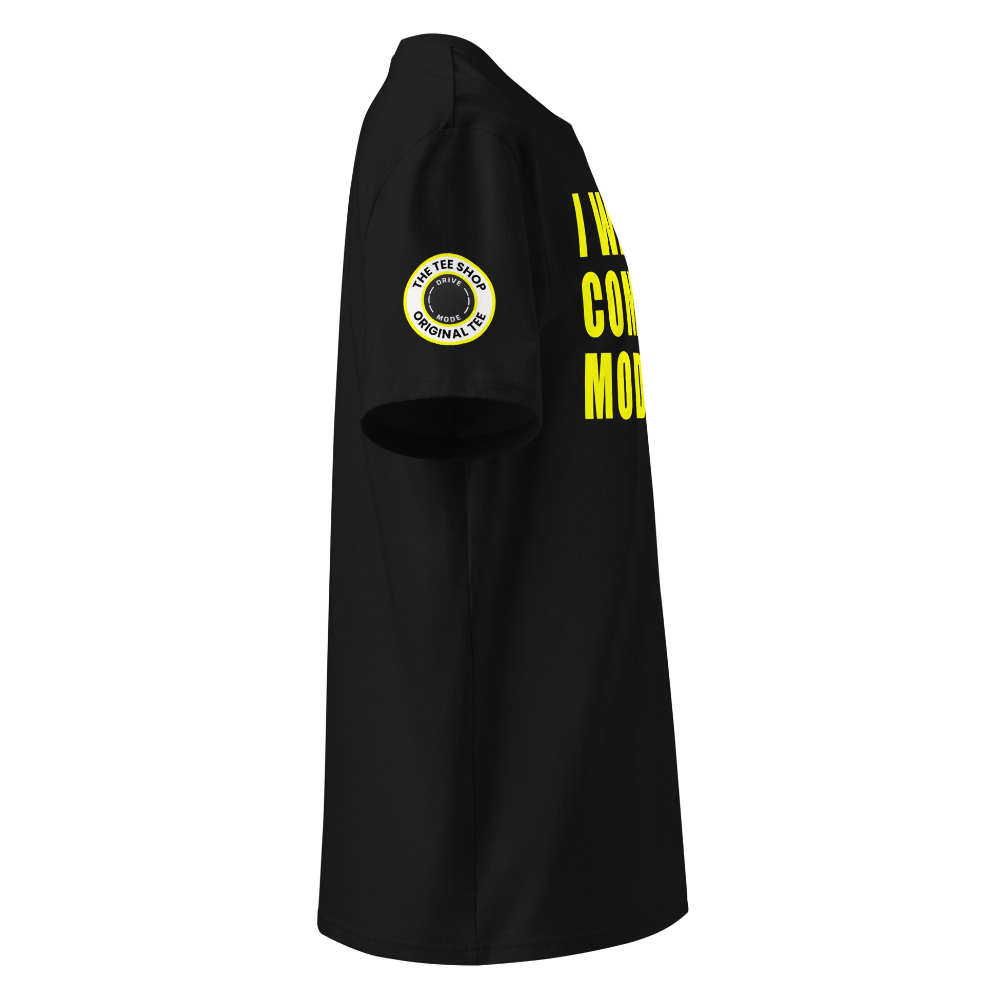 Right side view of black t-shirt showing The Tee Shop’s drive mode button logo patch on the sleeve and edge of the yellow “I WAS IN COMFORT MODE” chest print. DTF print, car culture style.