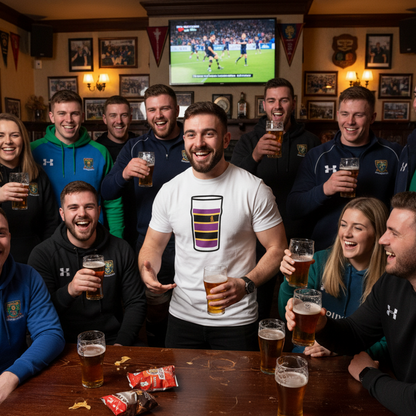 Man wearing white Instonians Mega Pint Rugby T-Shirt standing with teammates and supporters holding pints in a lively rugby clubhouse.