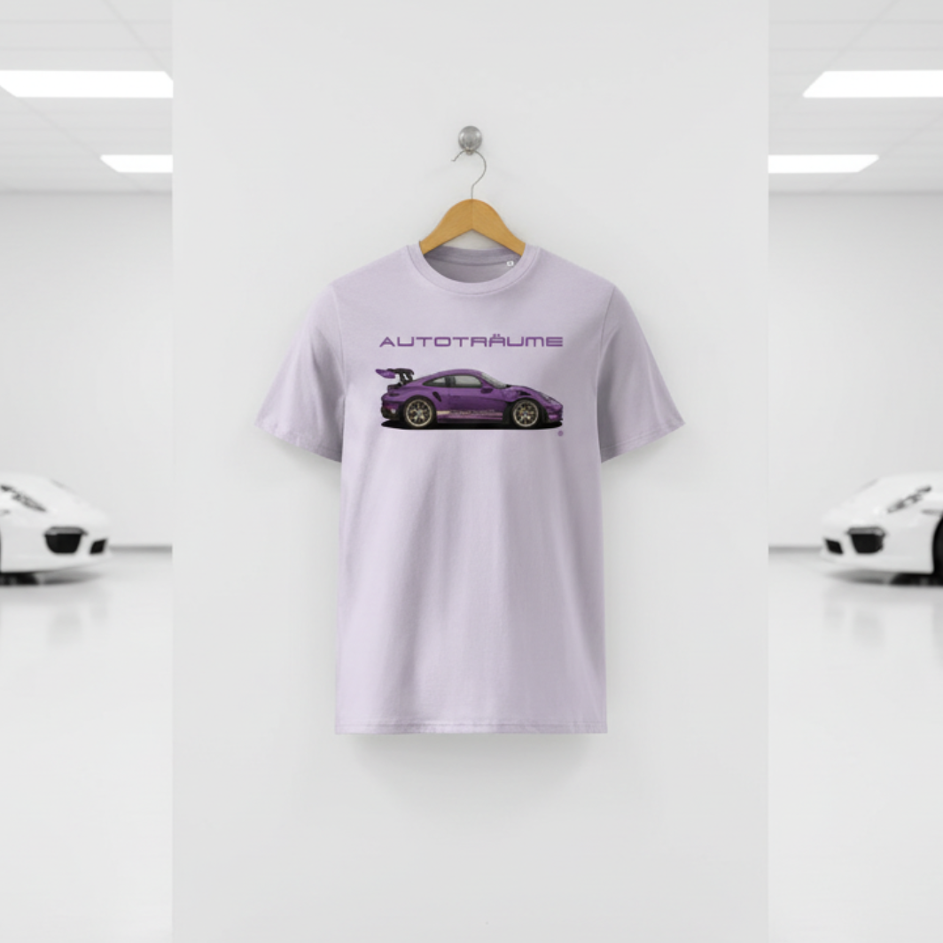 Pale lavender AUTOTRÄUME GT3 T‑shirt with a purple Porsche‑style car illustration hanging on a premium wooden hanger and silver wall peg against a central white wall in a bright sports car gallery, with a glossy white floor and blurred white and silver sports cars running down both sides.