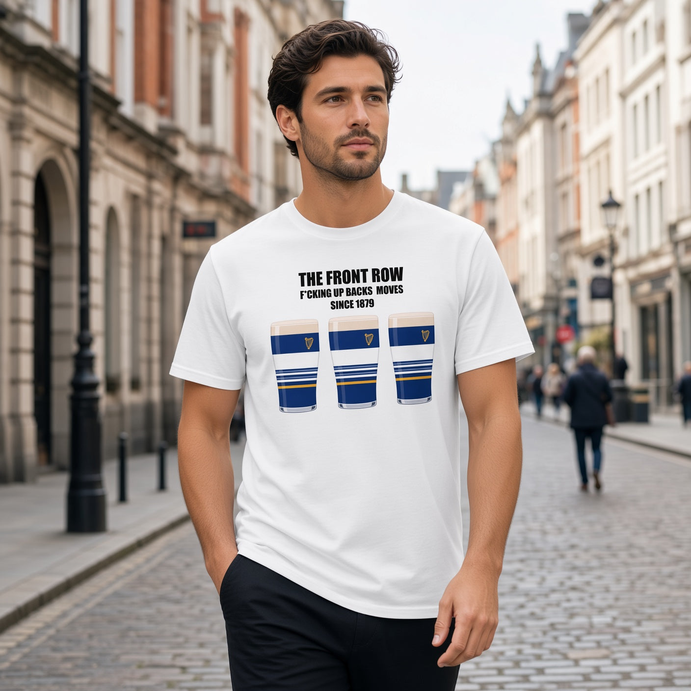 Male model wearing a white Leinster rugby t-shirt reading “The Front Row - F*cking Up Backs Moves Since 1879” with three blue striped pint graphics featuring a harp crest, photographed outdoors for Leinster supporters