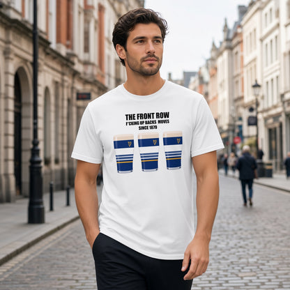 Male model wearing a white Leinster rugby t-shirt reading “The Front Row - F*cking Up Backs Moves Since 1879” with three blue striped pint graphics featuring a harp crest, photographed outdoors for Leinster supporters