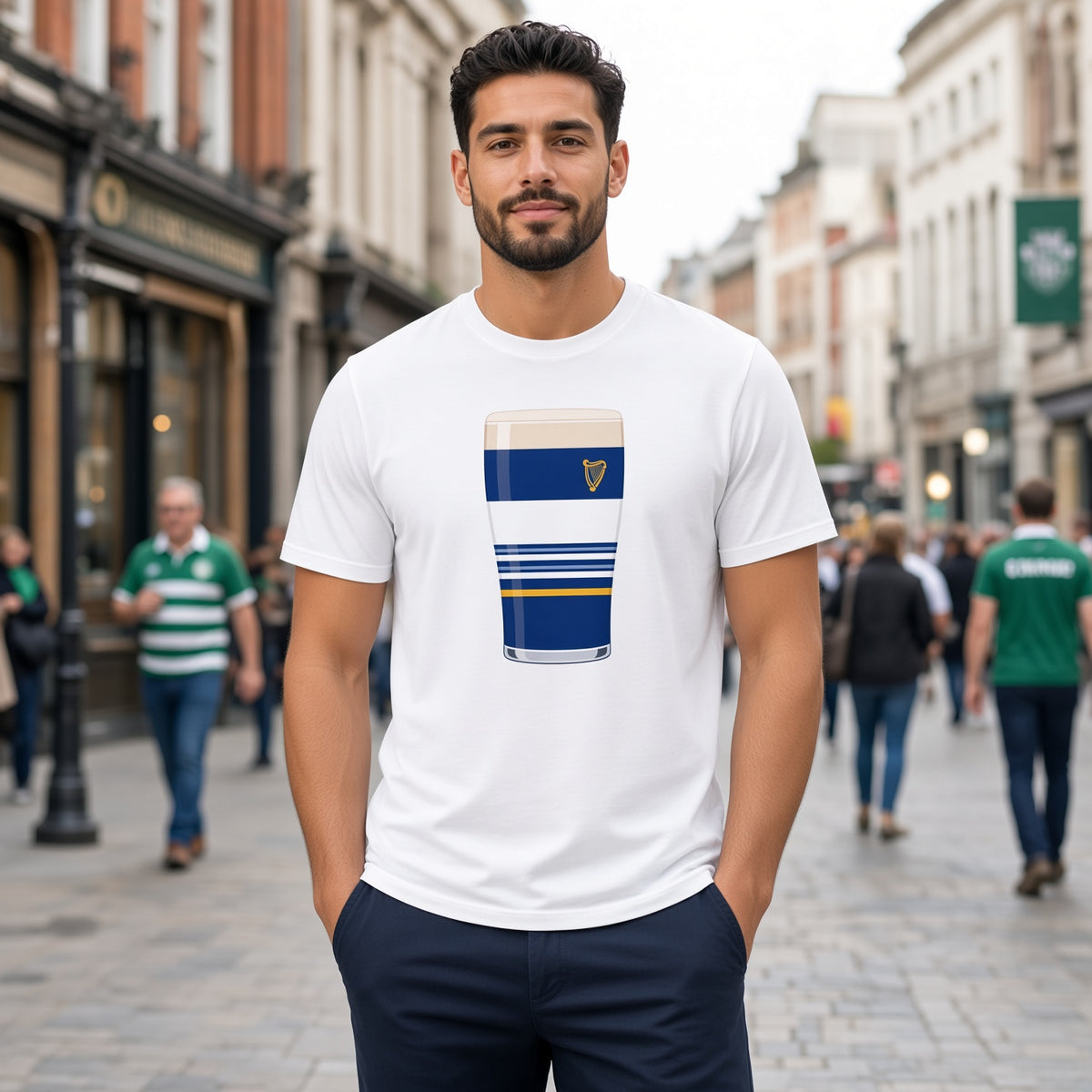 Male model wearing a white Leinster Striped Mega Pint rugby t-shirt with a blue pint glass graphic, white stripes, gold accent line and harp crest, photographed on a street with supporters for match day fanwear