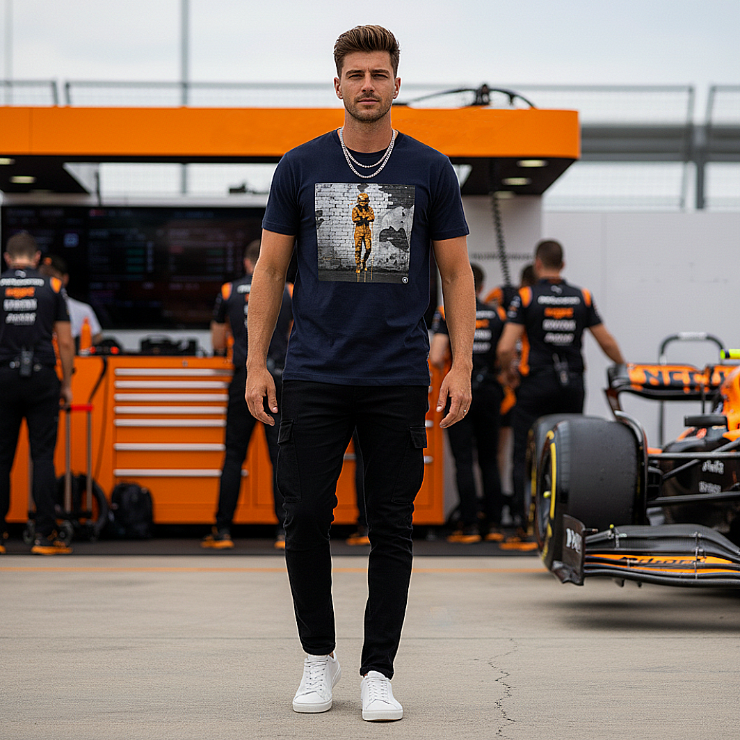 Male model wearing the French Navy organic cotton Papaya Driver Mood Graffiti Art F1 T-Shirt featuring a McLaren-inspired driver in vibrant papaya orange graffiti, standing with arms relaxed by his sides in a Papaya F1 paddock environment.