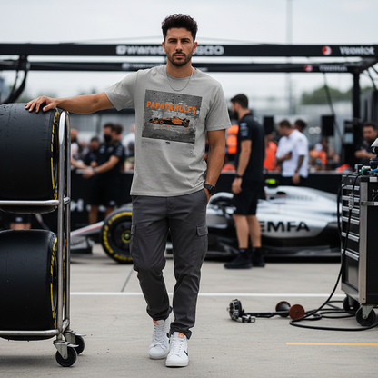 Male model wearing the heather grey organic cotton Papaya Rules 2.0 graffiti art F1 t-shirt without a jacket, styled casually in a motorsport paddock environment with motorsport props.