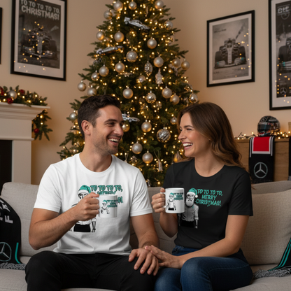 Male and female models wearing the Toto Wolff Merry Christmas T-Shirts (white and black versions) and holding the official mug, enjoying a festive scene with Mercedes F1 memorabilia and holiday decorations.