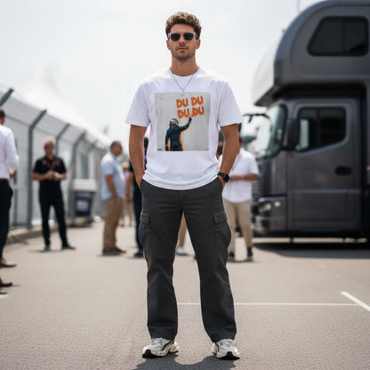 Man wearing TheTeeShop’s Max Series DU DU DU DU Graffiti T-Shirt featuring Max Verstappen spray-painting his famous chant, standing in a Formula 1 paddock surrounded by fans, perfect for Max Verstappen supporters and F1 enthusiasts.