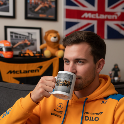 A male McLaren F1 fan in team gear enjoys coffee at home with the Papaya Series: Pit Stop Graffiti Mug. The perfect scene for any McLaren supporter, featuring bold street art and warm racing vibes.
