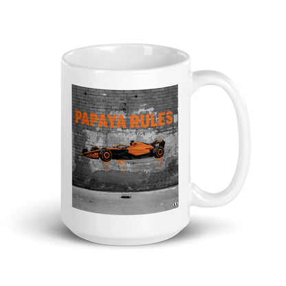White ceramic 15oz mug featuring a street art illustration of a papaya orange McLaren F1 car and “PAPAYA RULES” graffiti on a distressed brick wall.
