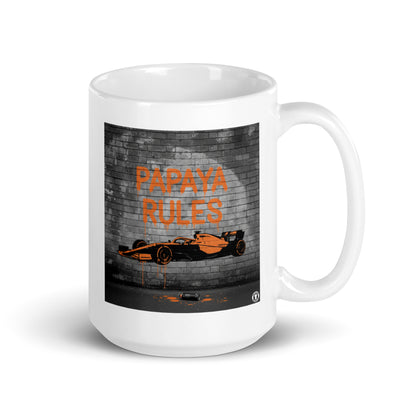White ceramic 15oz mug featuring a street art illustration of a papaya orange McLaren F1 car and “PAPAYA RULES” graffiti on a dark brick wall.