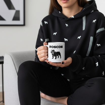 Female fan in modern or dog-themed homewear, enjoying a hot drink from the Roscoe Black Silhouette Mug while relaxing on the sofa with minimalist décor in the background.