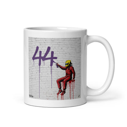 White ceramic 11oz mug featuring a street art illustration of a racing driver in Ferrari red overalls and a yellow helmet spray-painting a large purple 44 on a white brick wall, inspired by Lewis Hamilton and Ferrari.
