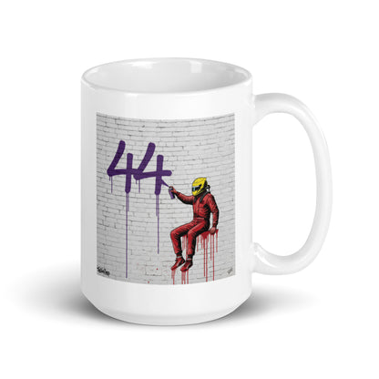 White ceramic 15 oz mug featuring a street art illustration of a racing driver in Ferrari red overalls and a yellow helmet spray-painting a large purple 44 on a white brick wall, inspired by Lewis Hamilton and Ferrari.