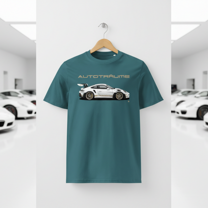 Teal blue unisex organic cotton AUTOTRÄUME GT3 RS T-shirt featuring a large, centred white Porsche-style GT3 RS car graphic with gold details hanging on a premium wooden hanger with a silver wall peg against a clean white wall panel in a bright modern sports car gallery with glossy floors and blurred white and silver sports cars on both sides.