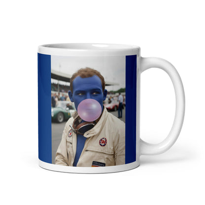 White ceramic 11oz mug with a bold blue border featuring a pop-art style portrait of Stirling Moss in a white racing suit, blue-tinted face, and blowing a pink bubblegum bubble, with a vintage racetrack scene in the background.