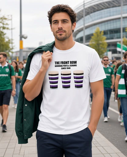 Male model wearing a white Terenure rugby t-shirt reading “The Front Row - Downing Pints & Scrums Since 1940” with three purple, black and white pint graphics, photographed in a Ireland rugby match day crowd setting