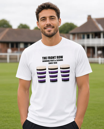 Male model wearing a white Terenure rugby t-shirt reading “The Front Row - Downing Pints & Scrums Since 1940” with three purple, black and white pint graphics, photographed at a rugby ground for Leinster match day supporters