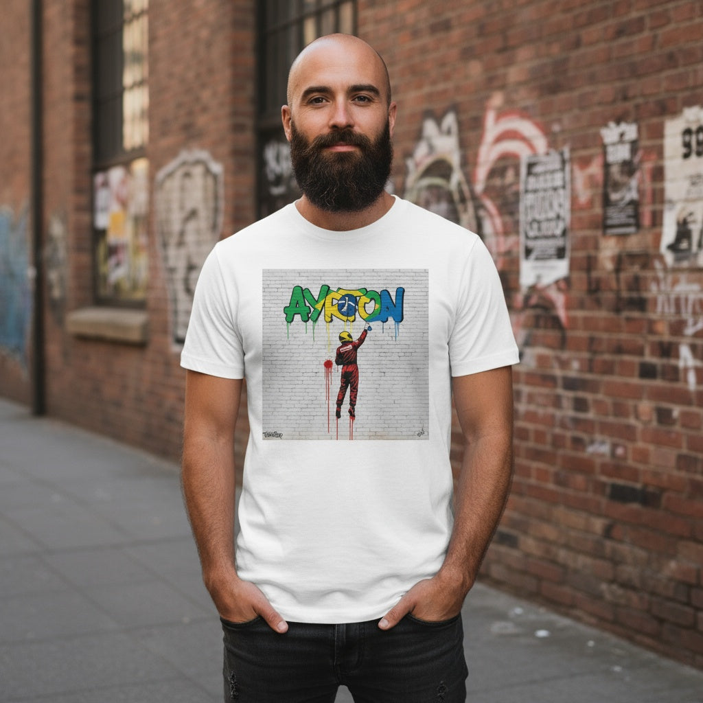 Man with beard wearing TheTeeShop’s Ayrton Senna street art graffiti t-shirt from the Paddock Collection, posing against a brick wall covered with urban graffiti and posters, showcasing motorsport-inspired streetwear.