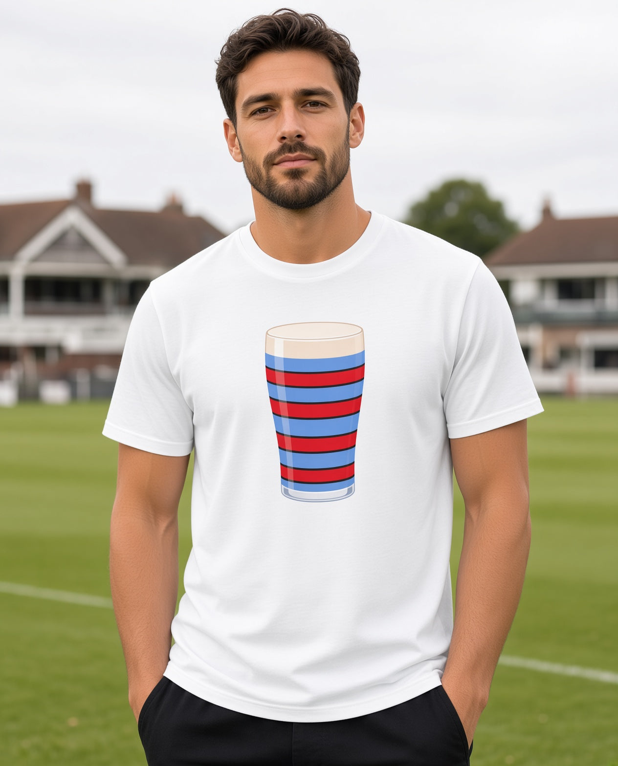 Male model wearing a white vintage Blackheath rugby Mega Pint t-shirt with a red and light blue striped pint glass graphic, photographed at a rugby ground for Blackheath match days and England supporters