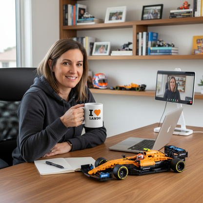 Person sitting at a desk with a laptop, toy car, and mug, in an office setting. Model is wearing a Lando Norris mug.